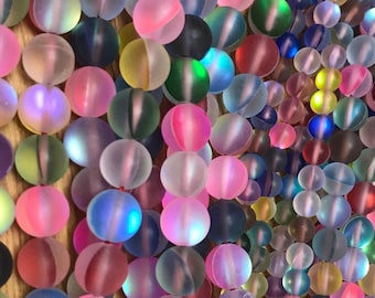 May include: A strand of iridescent glass beads in various colors, including pink, blue, green, and yellow. The beads are round and have a frosted finish.