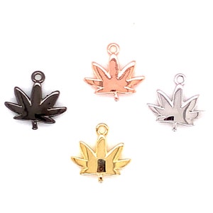 May include: Four metal leaf charms in black, rose gold, silver, and gold. Each charm has a loop at the top for attaching to jewelry. The charms are arranged against a white background.