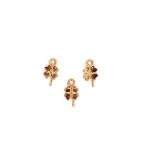 May include: Three gold-colored four-leaf clover charms with a loop at the top for attaching to jewelry or other crafts.