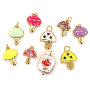 May include: A collection of colorful mushroom charms with gold-tone stems. The charms feature various designs, including polka dots, hearts, and gemstones. The mushroom caps are in shades of red, green, yellow, and purple.