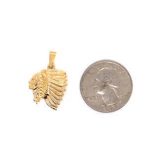 May include: Gold-toned pendant featuring a detailed profile of a Native American chief wearing a headdress. The pendant is shown next to a US quarter for size comparison.