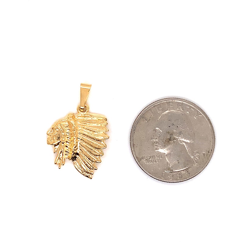 May include: Gold-toned pendant featuring a detailed profile of a Native American chief wearing a headdress. The pendant is shown next to a US quarter for size comparison.