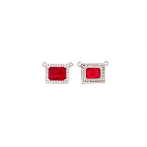 May include: Two silver-toned rectangular pendants with a vibrant red gemstone center. One pendant is surrounded by a halo of small, clear crystals. The other pendant has a decorative border. Both have small loops for attaching to a chain.