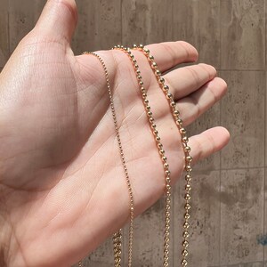 May include: Three gold ball chain necklaces of varying lengths and bead sizes.