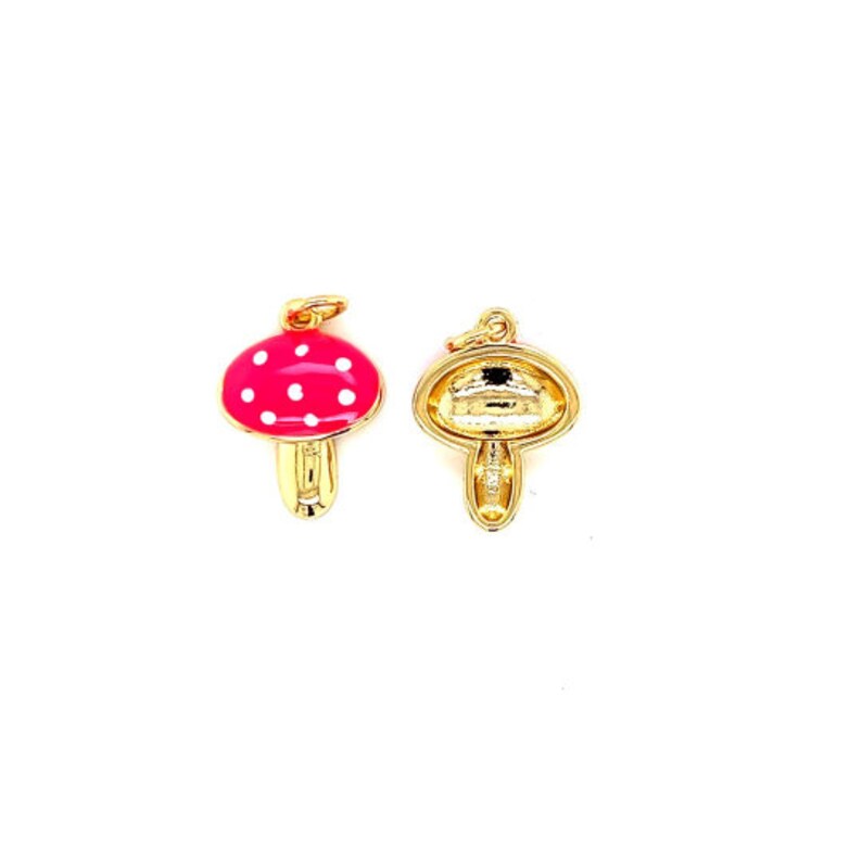 May include: Two mushroom charms. One charm is a bright pink with white polka dots and a gold-colored stem. The other charm is gold-colored, showing the back of the mushroom. Both charms have a small loop for attaching to a chain or bracelet.