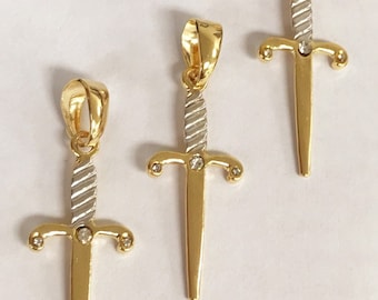 Pode incluir: Três pingentes de espada em tom dourado com detalhes de strass transparentes. As espadas têm um acabamento de dois tons com uma faixa prateada no centro.