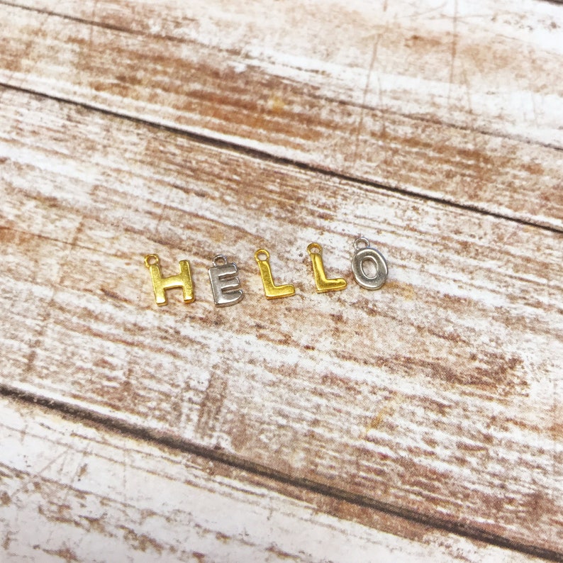 May include: Gold and silver letter charms spelling out the word "HELLO".