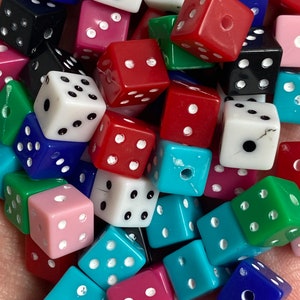 May include: A collection of colorful dice with white dots. The dice are made of plastic and are in various colors, including red, blue, green, pink, and white.
