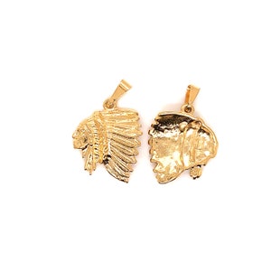 May include: Two gold-tone pendants, one shaped like a Native American headdress and the other shaped like a profile of a Native American person wearing a headdress.