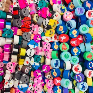 May include: A large collection of colorful, small, round polymer clay charms. The charms feature various animal, food, and geometric designs.