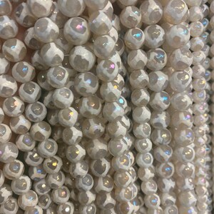 May include: A strand of white agate beads with iridescent shimmer. The beads are round and have a textured surface.