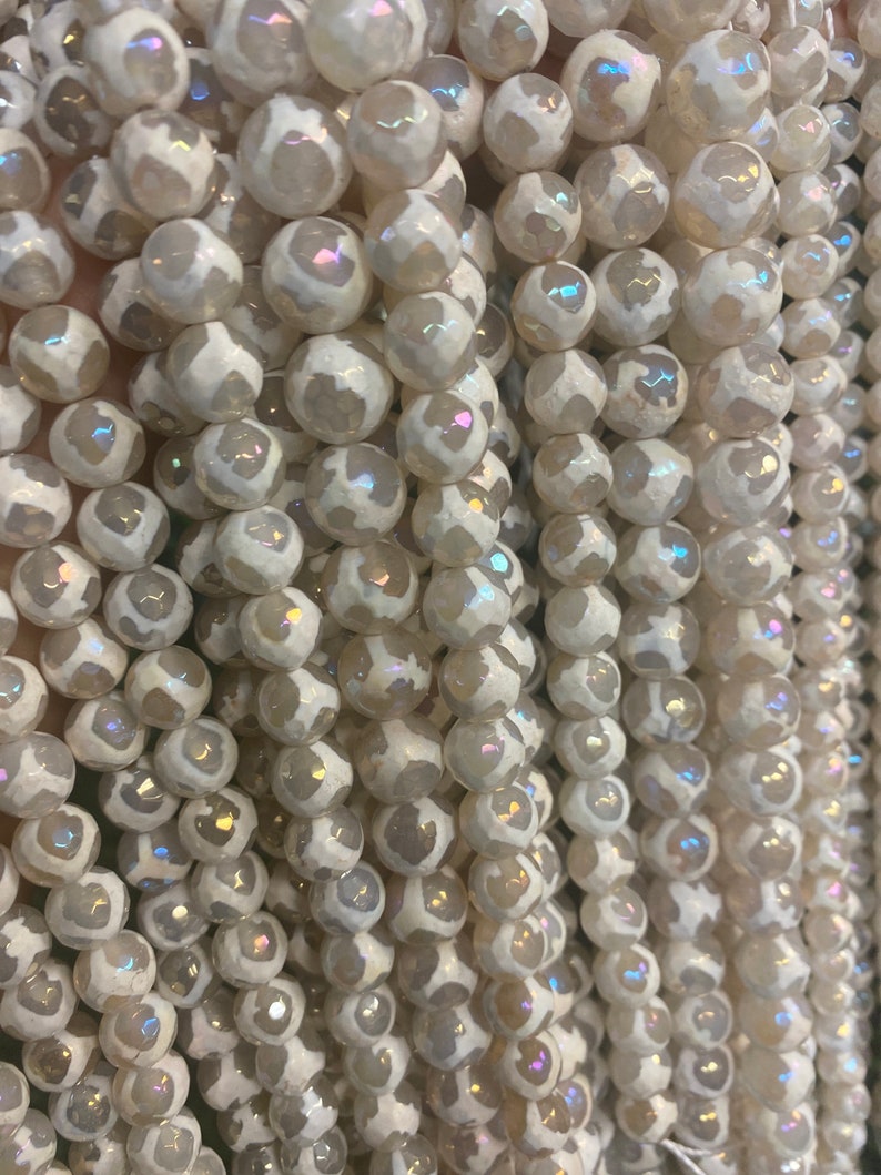 May include: A strand of white agate beads with iridescent shimmer. The beads are round and have a textured surface.