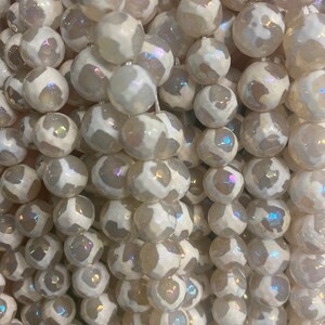 May include: A strand of white agate beads with iridescent shimmer. The beads are round and have a natural, organic look.