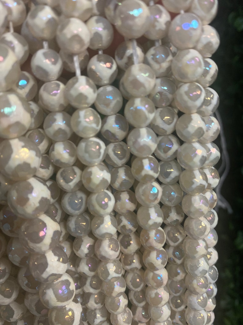 May include: A strand of white agate beads with iridescent shimmer. The beads are round and have a white and gray pattern.
