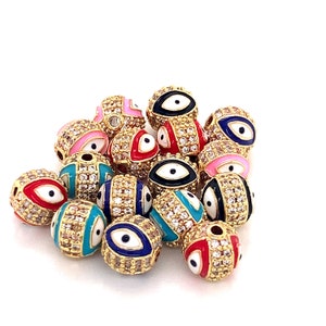 May include: A group of colorful, round beads with an evil eye design. The beads are gold-toned and have clear rhinestones around the edges. The evil eyes are in various colors, including blue, red, pink, and black.
