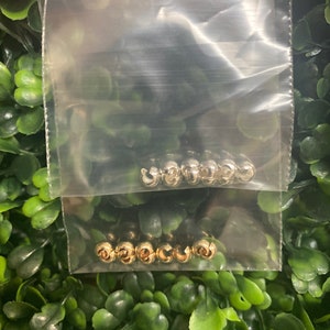 以下が含まれることがあります： 金と銀のジャンプリングが2つの袋に入っています。袋は透明なプラスチック製で、リングは積み重ねられています。