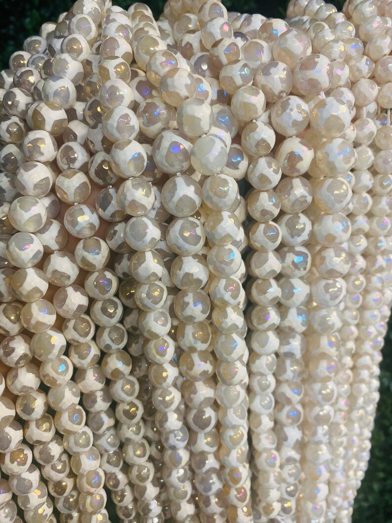 May include: A strand of white agate beads with iridescent shimmer. The beads are round and have a natural, organic look.