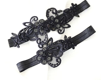 Könnte beinhalten: Ein Paar schwarze Strumpfhalter mit zarter Spitze und Paillettenbesatz.