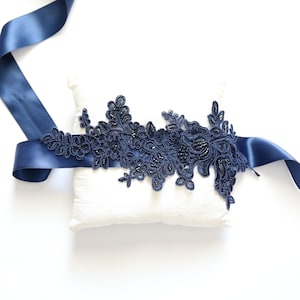 May include: Navy blue satin ribbon with a navy blue lace applique featuring floral designs and bead embellishments.