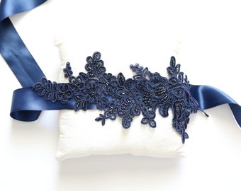 Könnte beinhalten: Navyblaues Satinband mit einer navyblauen Spitzenapplikation mit floralen Designs und Perlenbesatz.