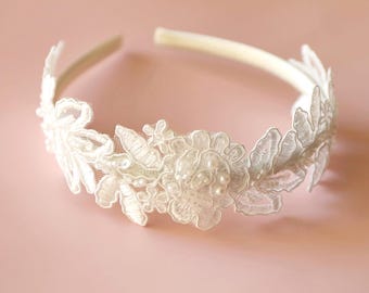 Könnte beinhalten: Elfenbeinfarbenes Haarband mit zarter floraler Spitze und Perlenakzenten. Das Spitzendesign umfasst Blätter und eine zentrale Blume, wodurch eine elegante und romantische Ästhetik entsteht. Perfekt für Hochzeiten oder besondere Anlässe.