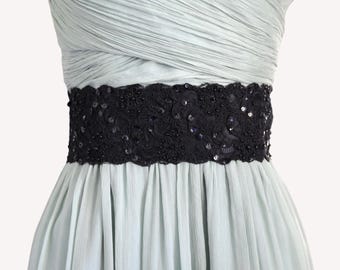 Könnte beinhalten: Ein blass mintgrünes Kleid mit trägerlosem Oberteil mit horizontalen Falten und einem breiten schwarzen Taillenband. Das Taillenband ist mit aufwendiger schwarzer Spitzenstickerei, kleinen schwarzen Perlen und schimmernden Pailletten verziert.