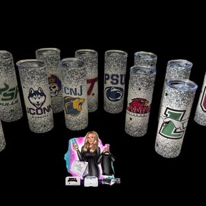 May include: A collection of glitter-covered tumblers featuring various college logos and mascots. The designs include logos for UConn Huskies, Penn State, and others. The tumblers are cylindrical and have a silver glitter finish.