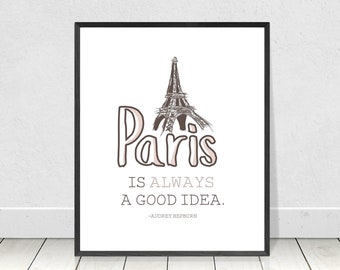 May include: A black framed print with a white background featuring a line drawing of the Eiffel Tower in Paris, France. The text "Paris is always a good idea." is written below the image, with the quote attributed to Audrey Hepburn.