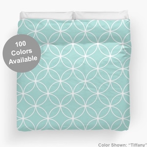 May include: A turquoise duvet cover with a white geometric pattern of overlapping circles. The text "100 Colors Available" is in a gray circle. The color shown is "Tiffany".