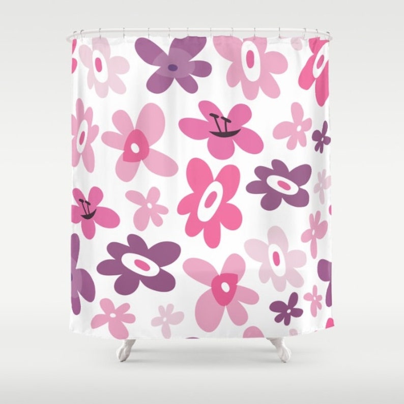 May include: A shower curtain with a white background and a pattern of pink and purple flowers. The flowers are all different shapes and sizes, and some have a smiley face in the center.