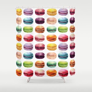 May include: A white shower curtain with a repeating pattern of colorful macarons. The macarons are arranged in rows and are various shades of pink, purple, green, yellow, and orange.