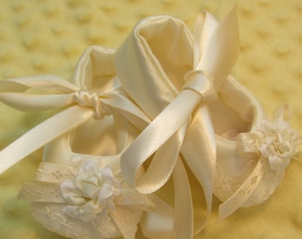 Off white satin baby shoes with lace trim bows and fabric flower