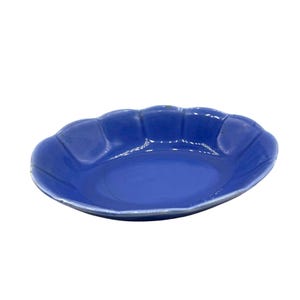 May include: A small, oval-shaped, blue ceramic dish with a scalloped rim. The dish has a glossy finish and a smooth interior. The color is a vibrant, solid blue. This decorative dish is suitable for serving small portions of food or as a decorative accent.