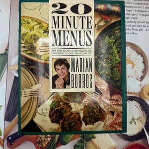 May include: A cookbook titled "20 Minute Menus" by Marian Burros, with a photo of the author. The cover is set against a backdrop of various dishes, including pasta, vegetables, and meat, suggesting a focus on quick and easy recipes.