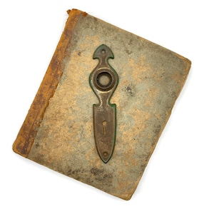May include: An antique book with a weathered, textured cover and aged, gilded edges. A vintage brass door escutcheon with a keyhole and decorative design is affixed to the book's cover, showcasing a classic, aged aesthetic.