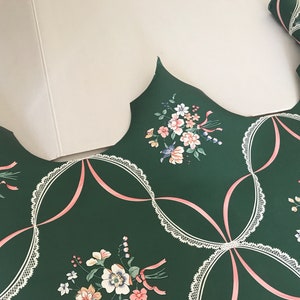 Puede incluir: Papel tapiz verde con un patr&oacute;n de encaje blanco y un dise&ntilde;o de cinta rosa. El papel tapiz presenta un patr&oacute;n floral con flores rosas, blancas y azules.