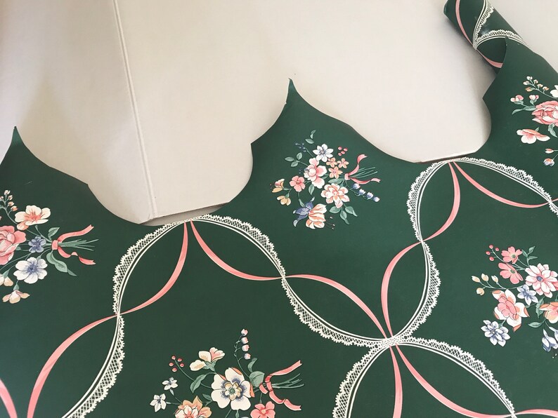 Puede incluir: Papel tapiz verde con un patr&oacute;n de encaje blanco y un dise&ntilde;o de cinta rosa. El papel tapiz presenta un patr&oacute;n floral con flores rosas, blancas y azules.