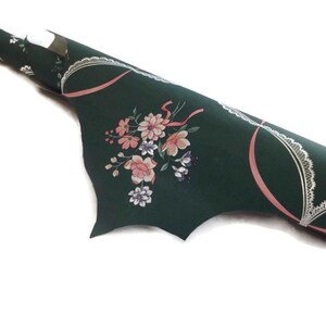 Puede incluir: Un rollo de papel tapiz verde con un lazo rosa y un dise&ntilde;o de encaje blanco. El papel tapiz presenta un patr&oacute;n floral con flores rosas, blancas y azules.