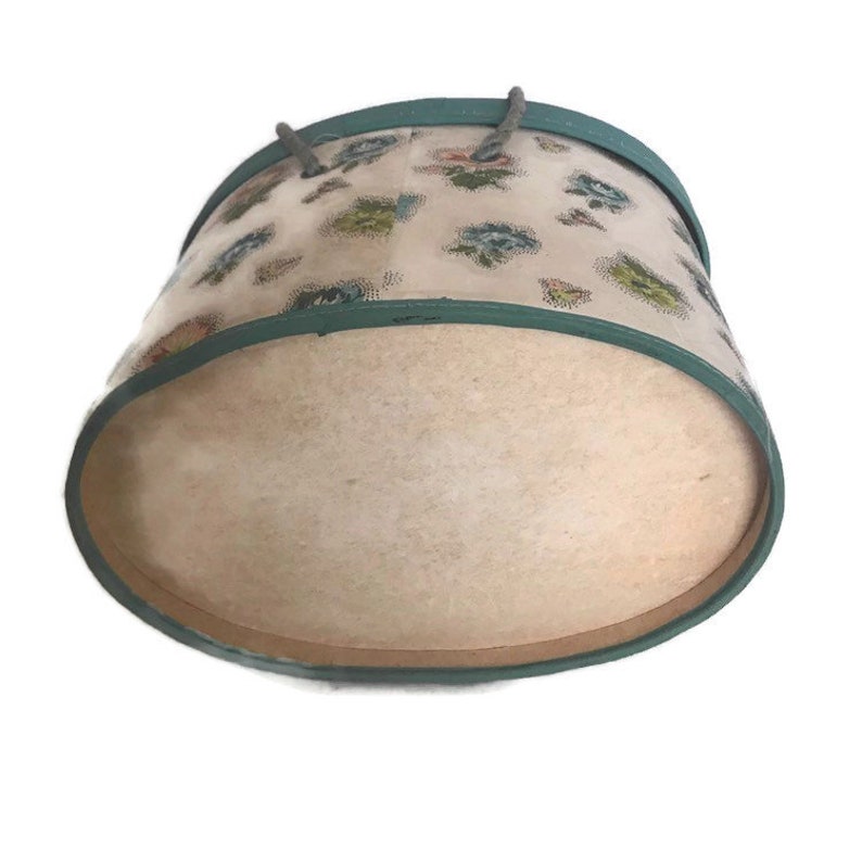May include: A vintage round hatbox with a floral pattern and a teal blue lid. The lid is open and the inside of the box is beige.