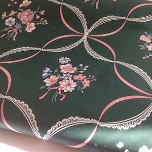 Puede incluir: Papel tapiz verde con un patr&oacute;n repetido de cintas rosas, encaje blanco y ramos de flores rosas, blancas y moradas.