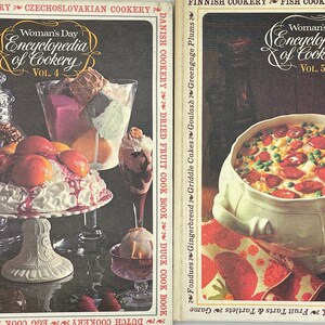 May include: Two vintage cookbooks, "Woman's Day Encyclopedia of Cookery," are displayed. Volume 4 features desserts, while Volume 5 showcases a casserole. The covers are in shades of brown, white, and red, with the titles in elegant script.