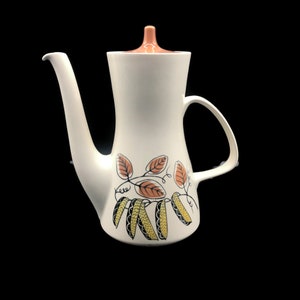May include: White ceramic coffee pot with a brown lid and a floral design featuring brown leaves and yellow pea pods.