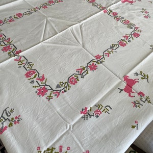 May include: White tablecloth with a pink and green embroidered floral pattern and a pink horse design.