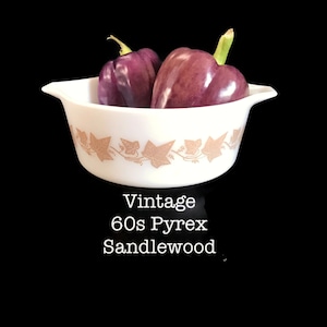 May include: Vintage 60s Pyrex casserole dish with a brown and white ivy pattern. The dish is filled with two purple bell peppers.