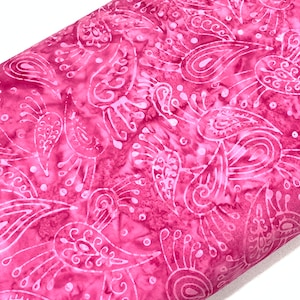 May include: Pink fabric with a white paisley pattern. The fabric has a soft, flowing texture and is perfect for crafting projects.
