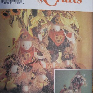 May include: Simplicity Crafts pattern featuring scarecrow dolls. The dolls have straw hair, hats, and sunflower accents. The pattern includes instructions for creating these fall-themed decorative items. The image also shows the pattern number and designer's name.