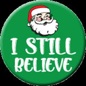 May include: Green button with a white outline and the text "I STILL BELIEVE" in white. A cartoon image of Santa Claus wearing a red hat is in the upper left corner.