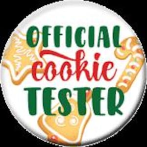 May include: A round, white button with the text "OFFICIAL cookie TESTER" in green and red. The button features illustrations of gingerbread cookies and a candy cane, evoking a festive holiday theme.