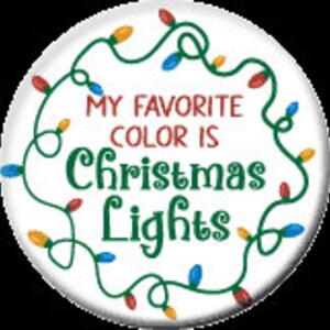 May include: A white button with a green wreath of colorful Christmas lights around the edge. The text inside the wreath reads "My favorite color is Christmas Lights".