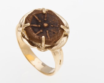 May include: A gold ring with a bronze coin set in the center. The coin has a starburst design.